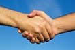 Shaking hands in front of blue sky