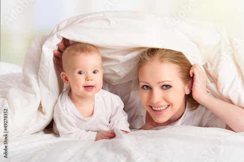 Photo: happy family. Mother and baby playing under blanket happy family. Mother and baby playing under blanket