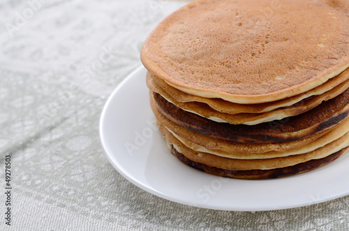 Photo: White plate with pankakes stack on the kitchen table White plate with pankakes stack on the kitchen table
