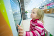 Adorable girl play computer game with touchscreen in supermarket