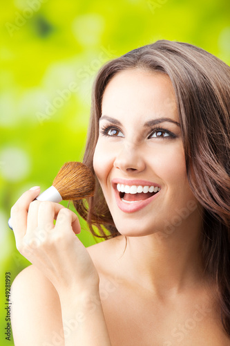 Photo: Smiling woman with make up brush, outdoor Smiling woman with make up brush, outdoor