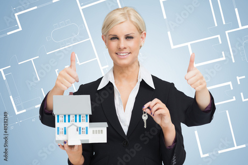 Photo: Multi-tasking estate agent holding keys and model home while giv Multi-tasking estate agent holding keys and model home while giv
