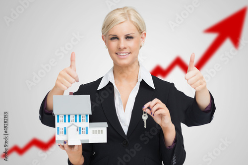 Photo: Multi-tasking estate agent holding keys and model house while gi Multi-tasking estate agent holding keys and model house while gi