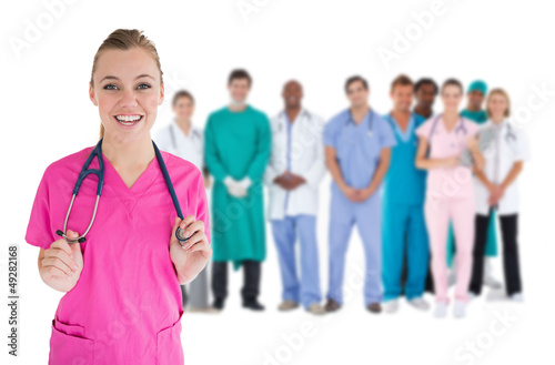 Photo: Smiling nurse with medical staff behind her Smiling nurse with medical staff behind her