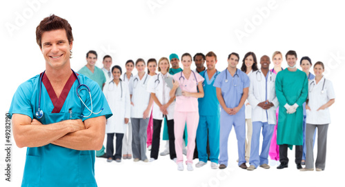 Photo: Smiling surgeon in front of a team of doctors standing together Smiling surgeon in front of a team of doctors standing together