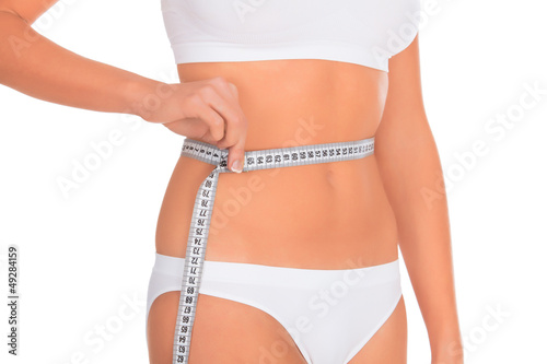 Photo: fit young woman measuring her waistline, white background fit young woman measuring her waistline, white background