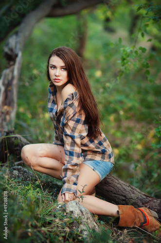Photo: Young girl in denim shorts and a multicolored shirt Young girl in denim shorts and a multicolored shirt