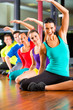 Group of people and instructor in gym stretching