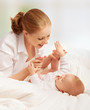 happy family. mother playing with her baby in bed