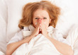 ill sick young woman sneezes  into a handkerchief in bed