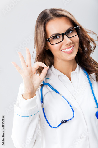 Photo: Female doctor with okay gesture, over grey Female doctor with okay gesture, over grey