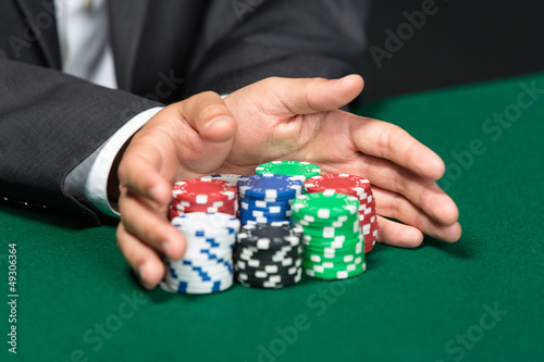 Photo: Poker player going "all in" pushing his chips forward Poker player going "all in" pushing his chips forward