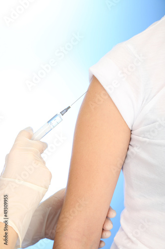 Photo: Doctor holding syringe with a vaccine in the patient shoulder, Doctor holding syringe with a vaccine in the patient shoulder,