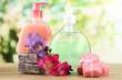 Liquid and hand-made soaps on wooden table, on green background