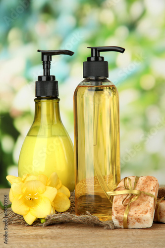 Photo: Liquid and hand-made soaps on wooden table, on green background Liquid and hand-made soaps on wooden table, on green background