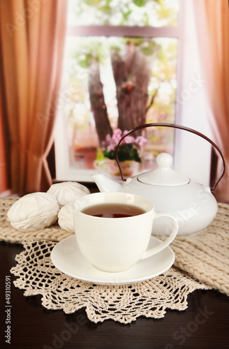 Photo: cup of tea with scarf on table in room cup of tea with scarf on table in room