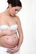 A pregnant woman with a smiley painted on her belly.