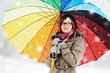 girl with colored umbrella standing in snowfall