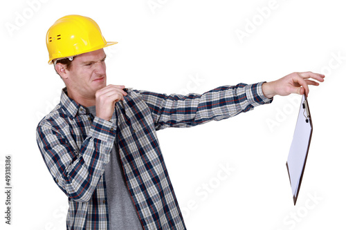 Photo: Construction worker holding a distasteful clipboard Construction worker holding a distasteful clipboard