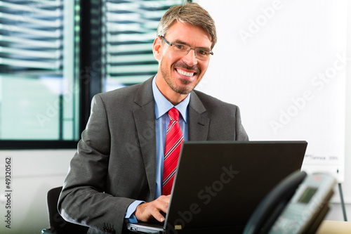 Photo: businessperson with laptop in his business office businessperson with laptop in his business office