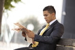 Foto: Businessman reading his newspaper next to his office building Businessman reading his newspaper next to his office building