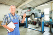 Photo: Mechanic holding a car key atauto repair shop during an automobi Mechanic holding a car key atauto repair shop during an automobi