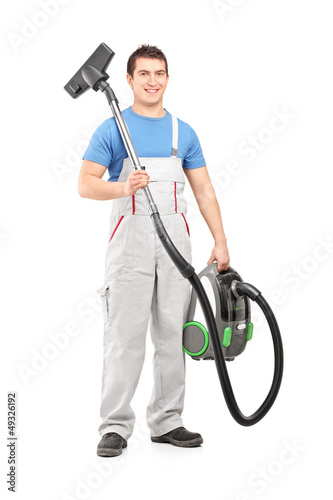 Photo: Full length portrait of a young male worker holding a vacuum cle Full length portrait of a young male worker holding a vacuum cle