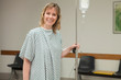 Smiling woman holding a drip stand while walking 