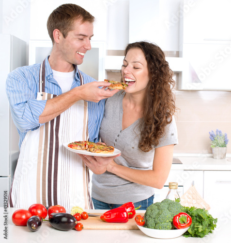 Photo: Happy Couple Eating Pizza. Cooking Together Happy Couple Eating Pizza. Cooking Together