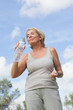 Smiling mature woman in sportswear drinking water