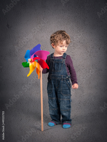 Photo: Young kid portrait with windmill over grunge background. Young kid portrait with windmill over grunge background.