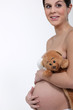 Pregnant woman hugging her belly and a teddy bear