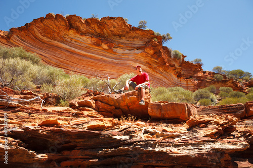 Photo: Man sitting bottom of colourful layered rock Man sitting bottom of colourful layered rock