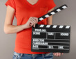 Movie production clapper board in hands on grey background