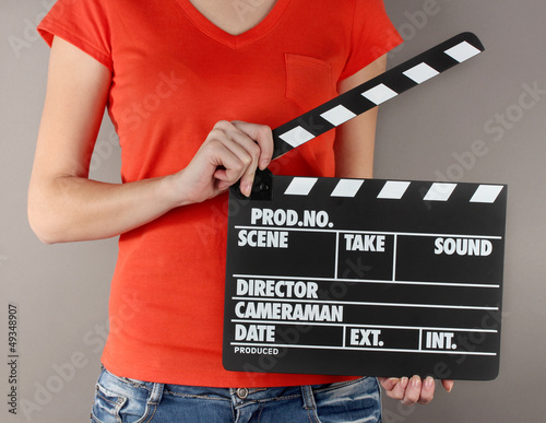 Photo: Movie production clapper board in hands on grey background Movie production clapper board in hands on grey background