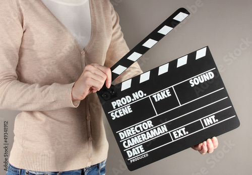 Photo: Movie production clapper board in hands on grey background Movie production clapper board in hands on grey background