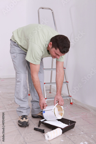Photo: Decorator pouring paint into a tray Decorator pouring paint into a tray
