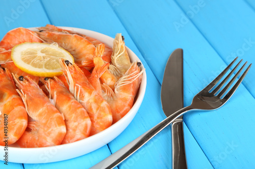 Photo: Shrimps with lemon on plate on wooden table close-up Shrimps with lemon on plate on wooden table close-up
