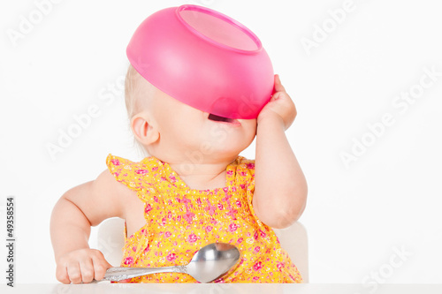 Photo: Little girl with a pink plate, on a gray background Little girl with a pink plate, on a gray background