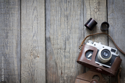 Photo: Old retro camera on vintage wooden boards abstract background Old retro camera on vintage wooden boards abstract background