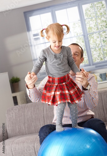 Photo: Little girl balancing on fit ball father helping Little girl balancing on fit ball father helping