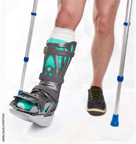Photo: Man with a broken leg with Crutches on a white background Man with a broken leg with Crutches on a white background