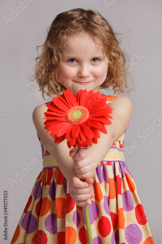 Photo: Happy little girl gives a flower to someone Happy little girl gives a flower to someone