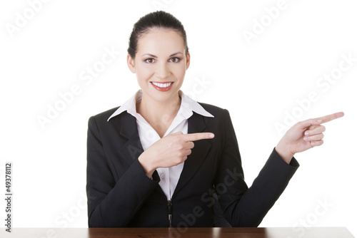 Photo: Businesswoman at the desk pointing to empty copy space Businesswoman at the desk pointing to empty copy space