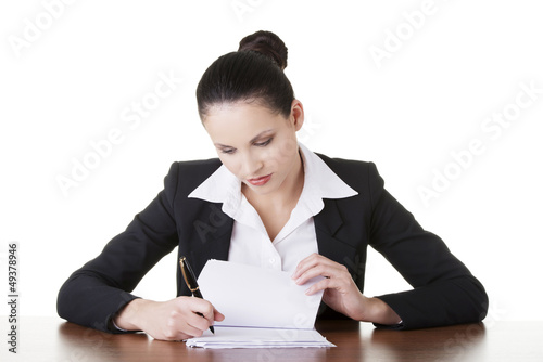 Photo: Businesswoman sitting at desk and writing. Businesswoman sitting at desk and writing.