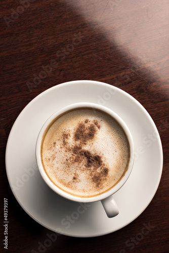 Photo: A cup of coffee on a wooden table top view A cup of coffee on a wooden table top view