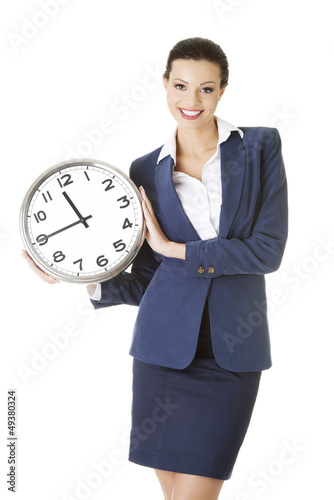 Photo: Happy young business woman holding office clock Happy young business woman holding office clock
