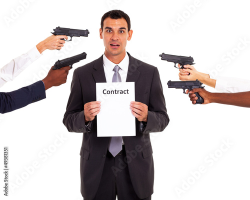 Photo: businessman holding forced contract at gun point businessman holding forced contract at gun point