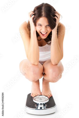Photo: Young woman sitting on her haunches on a scale Young woman sitting on her haunches on a scale