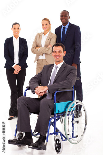 Photo: businessman in wheelchair with colleagues in background businessman in wheelchair with colleagues in background